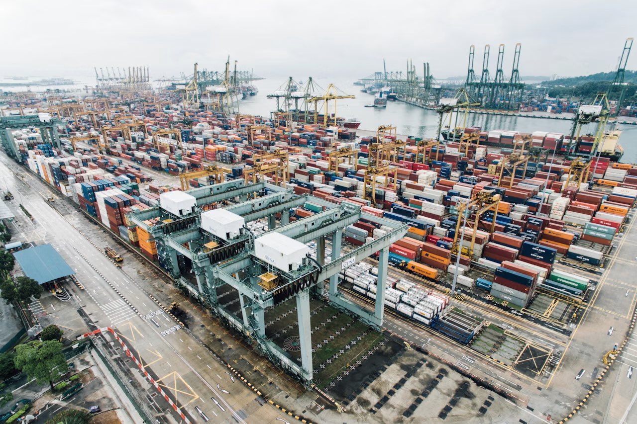 Containerterminal met opgestapelde containers en portaalkranen vanuit de lucht